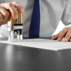 Dłoń z pieczątką nad dokumentem. KNF rekomendacja s. - oficjalne zatwierdzenie.
