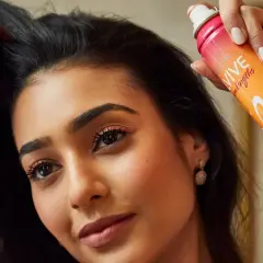 Mujer con pelo graso usa spray de champú seco para dar volumen y frescura.