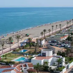 Vista aérea de la playa de las salinas, con gente disfrutando del sol y el mar, palmeras y edificios turísticos.