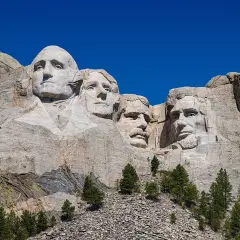 Las caras de cuatro presidentes de EE.UU. talladas en el **Monte Rushmore**, bajo un cielo azul intenso.