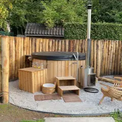 Eine rustikale Whirlpool Ecke im Garten gestalten: Holzzaun, Holzverkleidung, Holzstufen, Holzbänke und ein Metallofen schaffen Gemütlichkeit.