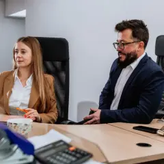 Kobieta i mężczyzna w biurze pracują przy komputerach.