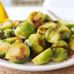 Plato de coles de Bruselas al horno, doradas y tiernas, con trocitos de bacon crujiente. Un manjar irresistible.