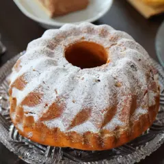 Puszysta babka drożdżowa, jak z babcinego przepisu, oprószona cukrem pudrem, na kryształowej paterze.