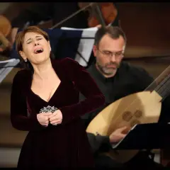 Wokalistka z pasją wykonuje swoje zajęcia wokalne, towarzyszy jej muzyk grający na lutni.