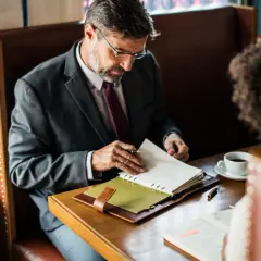 Mężczyzna w garniturze przegląda notatki, być może zastanawia się, czy novum dzwoni do pracodawcy.