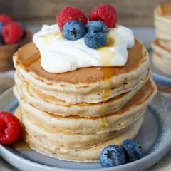 Fluffige Bananenpfannkuchen mit Sahne, Beeren und Honig. Ein köstlicher Frühstückstraum!