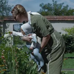 Kobieta w zielonej sukience pokazuje dziecku kwiaty. Scena jak z mądrych filmów wartych obejrzenia, pełna czułości i piękna natury.