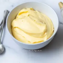 Crema pasticcera con panna, soffice e vellutata, pronta per farcire dolci. Accanto, cucchiaini d'argento e sac à poche.