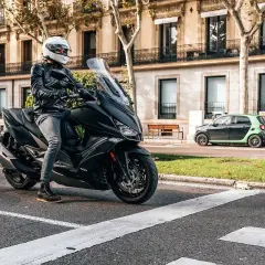 Conductor con casco blanco en un scooter negro, listo para rodar. Una imagen que evoca las mejores marcas de motos y la libertad en la ciudad.
