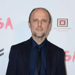 Łukasz Simlat, znany z wielu polskich filmów, na tle napisu "JUGA" i logo Polskiego Instytutu Sztuki Filmowej.