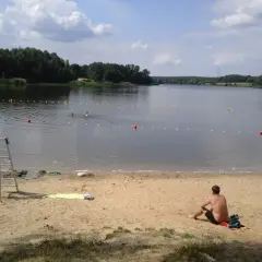 Słoneczny dzień nad zalewem Rybnik. Kąpielisko z ratownikiem, plażą i ludźmi kąpiącymi się w wodzie.