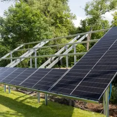 Montaż paneli fotowoltaicznych na solidnej konstrukcji. Instalacja w ogrodzie, gotowa do zbierania energii słonecznej.