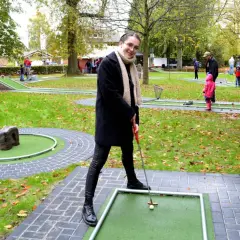 Frau spielt Minigolf in Hennef, im Hintergrund spielen weitere Personen.