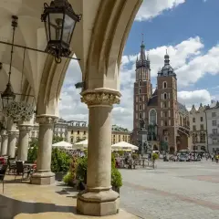 Urokliwy widok na Rynek Główny w Krakowie. Widać Sukiennice, Kościół Mariacki i ludzi spacerujących po placu.