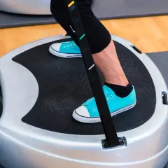 Kobieta ćwiczy na platformie wibracyjnej, by uniknąć skutków ubocznych braku ruchu.