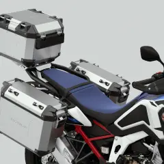 Detalle de una moto Honda con tres maletas de equipaje plateadas, listas para una aventura.