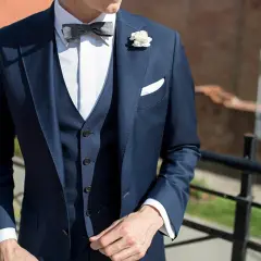 Eleganckie stylizacje z kamizelką pikowaną: granatowy garnitur, biała koszula, szara mucha i biała butonierka.