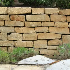 Eine rustikale Natursteinmauer bauen, die mit Lavendel und Steinen verziert ist.