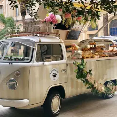 Un furgone vintage allestito per un aperitivo fuori chiesa matrimonio, con fiori e dolci.