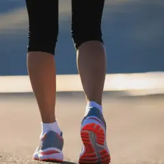 Nogi w butach do biegania na tle zachodzącego słońca. Ile spaceru dziennie?
