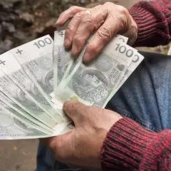 Dłonie trzymające banknoty 100 zł. Może to być wypłata renty inwalidzkiej.