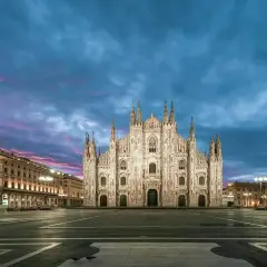 Majestatyczna katedra Duomo w Mediolanie nocą, oświetlona pod purpurowo-niebieskim niebem.