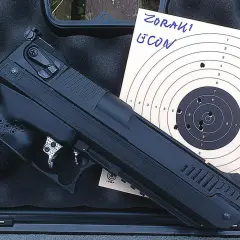 Pistolet Zoraki HP-01 Ultra obok tarczy strzeleckiej z widocznymi trafieniami na 10 metrów.