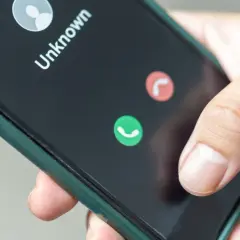 Dłoń trzyma smartfon z ekranem pokazującym nieznane połączenie. Zastanawiasz się, jak zastrzec numer jednorazowo?
