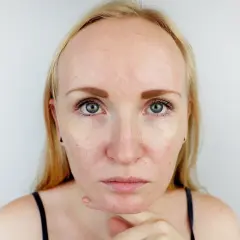 Blondynka z niejednolitą cerą, zastanawia się, co zrobić, żeby twarz się nie świeciła po nałożeniu podkładu.