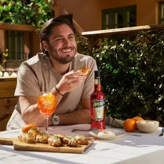 Man njuter av en Aperol Spritz och tilltugg utomhus.