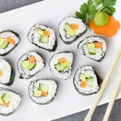 Tykwa sushi z awokado, ogórkiem i marchewką, podana z wasabi i ozdobą z marchewki.