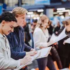 Unga människor skriver på papper vid ett event om framtida yrken att satsa på.