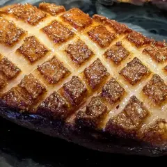 Magret de canard au four, la peau grillée en losanges, prête à être dégustée.