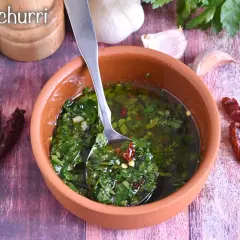 Salsa chimichurri fresca in ciotola di terracotta, con aglio, peperoncino secco e prezzemolo.