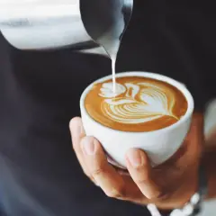 Un barista crea un disegno a latte art su un cappuccino. Latte versato nel caffè per un cappuccino prima latte o caffè perfetto.