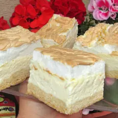 Sernik z rosą z wiaderka na dużą blachę, puszysty i pyszny, z bezą i kwiatami w tle.