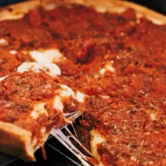 Ein Stück einer tiefen Chicago Style Pizza mit geschmolzenem Käse wird herausgehoben.