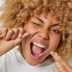 Donna con capelli ricci usa il filo interdentale per una pulizia perfetta.