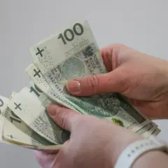 Dłonie trzymające polskie banknoty 100 i 200 zł.
