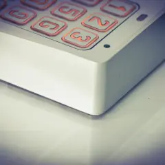 Zbliżenie na klawiaturę domofonu z podświetlanymi na pomarańczowo przyciskami.