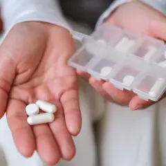 Dłonie trzymające tabletki i pojemnik na leki. Uważaj na przedawkowanie cynku, zbyt wiele suplementów może być szkodliwe.