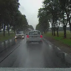 Deszczowa droga, samochód z przodu ma włączone światła mijania, a nasz samochód z tyłu ma włączone światła dzienne.