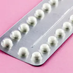 Eine Blisterpackung mit weißen Pillen auf rosa Untergrund. Die Pillen sind bereit, um sie durchzunehmen.