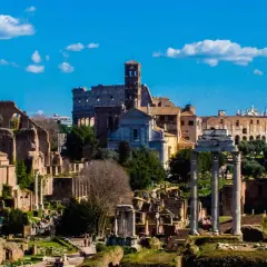 Il Foro Romano, un'istantanea di un viaggio a Roma 48h. Rovine antiche, il Colosseo e il cielo azzurro con nuvole bianche.