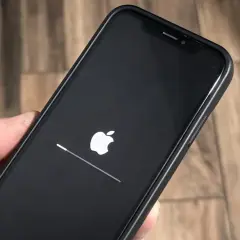 iPhone z logo Apple i paskiem postępu, aktualizacja iOS 26.3 w toku.