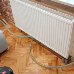 Profesjonalne płukanie instalacji grzewczej w Warszawie. Sprzęt do czyszczenia podłączony do grzejnika.
