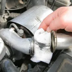 Ręka czyści szmatką metalową rurę, na której widać ślady oleju w intercoolerze.
