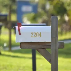 A white mailbox with the number 2204, mounted on a wooden post, ready for mail delivery. This image could be a visual guide on how to install a mailbox.