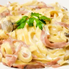 Pasta carbonara con setas y bacon, cremosa y deliciosa, coronada con perejil fresco.